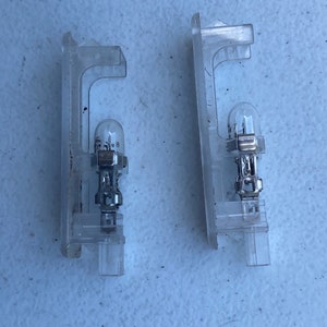 May include: Two clear plastic light bulb holders with silver metal clips and clear light bulbs.