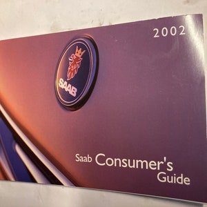 May include: A purple and silver Saab Consumer's Guide booklet featuring the Saab logo and the year 2002 printed on the cover.