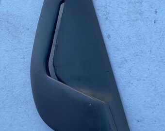 Könnte beinhalten: Ein dunkelgraues, gebogenes Kunststoff-Autoteil mit einer rechteckigen Öffnung. Das Teil hat eine glatte, matte Oberfläche und eine abgerundete Ober- und Unterseite. Wahrscheinlich ein Zierteil oder eine Innenraumkomponente.