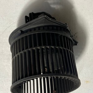 Puede incluir: Motor de soplador de coche de plástico negro con una jaula de ventilador circular y una carcasa de plástico negro.