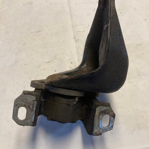 May include: Black rubber engine mount with metal brackets. The mount is designed to reduce vibration and noise from the engine.