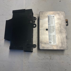 May include: A black plastic box and a silver metal box with a label that reads "LG AST PART NO. 3905170P AST PART NO. 3905170P".