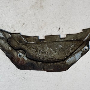 Peut inclure: Une pièce de voiture en métal argenté avec une surface texturée et plusieurs trous. La pièce est en forme de croissant de lune et a un bord légèrement incurvé.