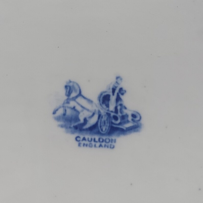 May include: A blue and white illustration of a horse-drawn chariot with a driver. The text "CAULDON ENGLAND" is below the illustration. The image is on a white background.