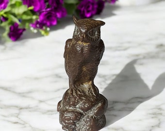 May include: A bronze-colored owl figurine, perched on a textured base. The owl has detailed feathers and a focused gaze. The sculpture is approximately 5 inches tall, showcasing a classic, decorative style.