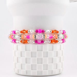 Pink Ginham Armbandkollektion: Rosa und orangefarbene elastische Perlenarmbänder