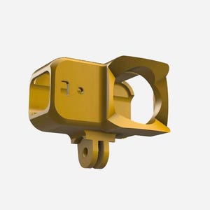 May include: A gold-colored, rectangular camera housing with a circular opening and a mounting bracket. The housing has a boxy shape with rounded edges and several small holes. The bracket is located on the bottom of the housing.