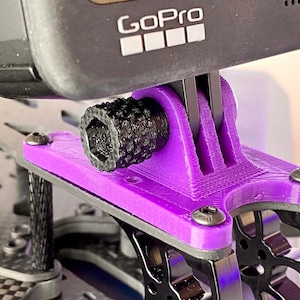 May include: Purple 3D printed GoPro mount with a black knob and a GoPro camera attached. The mount is attached to a black carbon fibre frame.