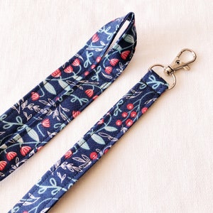 May include: A blue and white floral patterned lanyard with a silver swivel clip.