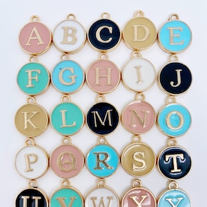 May include: A set of 26 gold-toned alphabet letter charms with colorful enamel. Each charm features a different letter of the alphabet, from A to Z. The charms are perfect for adding a personalized touch to jewelry, keychains, or other crafts.