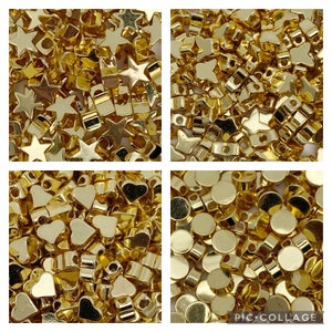 May include: Assortment of gold-coloured metal beads in various shapes, including stars, hearts, and circles. The beads are small and perfect for jewellery making or crafting.