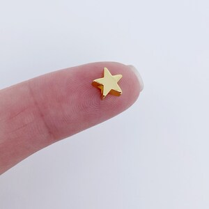 May include: A small gold star charm, ideal for adding a touch of sparkle to jewellery or crafts.