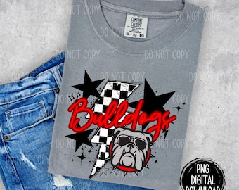 May include: A gray t-shirt with a red and white checkered lightning bolt design. The text "Bulldogs" is in red with a white outline. A bulldog wearing sunglasses is in the center of the design.