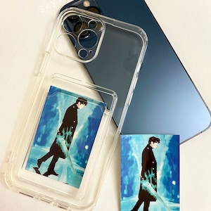 May include: A clear phone case with a photo of a man in a black coat and blue background. The photo is in a clear pocket on the back of the case. The case is on top of a dark blue phone.
