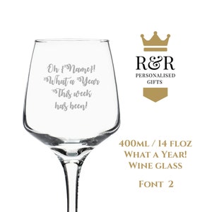 Op de afbeelding: Een helder glazen wijnglas met een gouden kroon en de tekst "R&R Gepersonaliseerde Geschenken" aan de zijkant. Het glas is gegraveerd met de tekst "Oh {Name}! Wat een jaar Deze week was!" en de tekst "400ML / 14 FLOZ WAT EEN JAAR! WIJNGLAS LETTERTYPE 2".