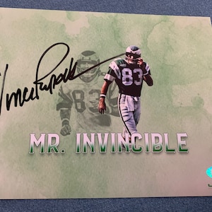 May include: A signed photograph of a football player wearing a green and white uniform with the number 83 on the front. The player is running with the ball. The signature is "Vince Papale" and the text "MR. INVINCIBLE" is below the player. The image has a PSA authentication sticker in the bottom right corner.