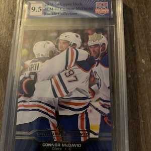 Puede incluir: Una tarjeta de hockey clasificada con Connor McDavid, un jugador de los Edmonton Oilers. La tarjeta es del set Rookie Collection Upper Deck 2015-16 y est&aacute; clasificada con un 9,5 por Beckett Grading Services.