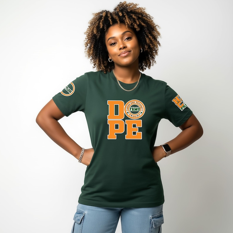 May include: A dark green t-shirt with the word "DOPE" in orange block letters. The shirt also features a circular logo and a patch on the sleeves. The person is wearing a gold chain and a watch.