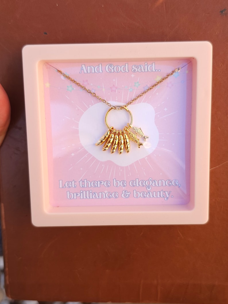May include: A gold necklace with a charm that says "And God said... Let there be elegance, brilliance & beauty."