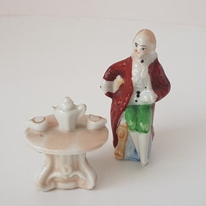 antique porcelain miniature seated gentleman with table, dolls house?