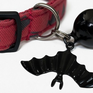 A red collar with a black bat-shaped charm attached to it.