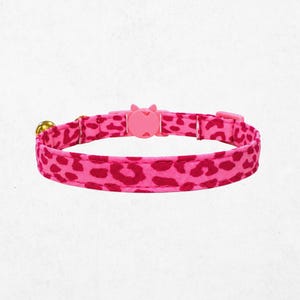 A pink leopard print cat collar with a bell attached.