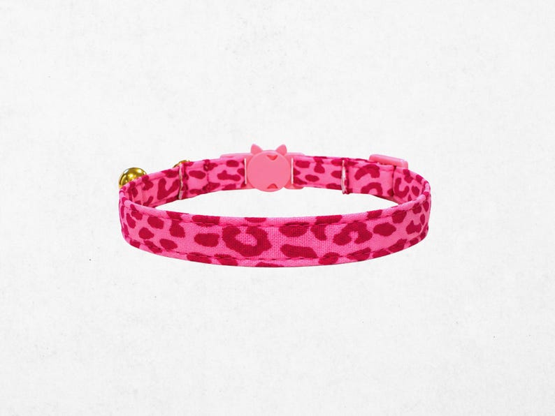 A pink leopard print cat collar with a bell attached.