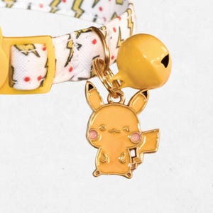 A gold-colored cat collar with a bell attached to it, featuring a small, cartoonish-like cat charm.
