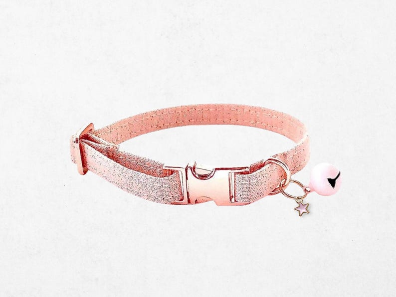 A pink glittery collar with a bell attached, featuring a star charm.