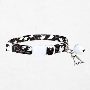 A black and white cat collar with a bell attached, featuring a repeating pattern of cat silhouettes.