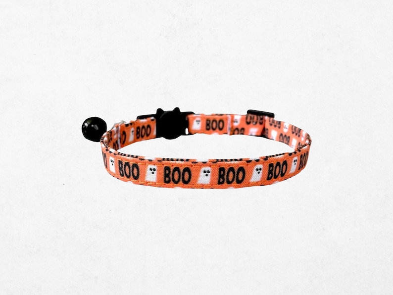 A cat collar with a repeating pattern of the word "BOO" in black letters, along with ghost-like silhouettes in orange and white.