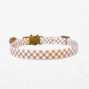 A checkered cat collar with a buckle and bell attached.