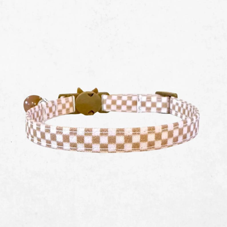 A checkered cat collar with a buckle and bell attached.