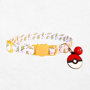 A white and yellow patterned dog collar with a yellow buckle and a red and white Pokemon-themed charm attached.