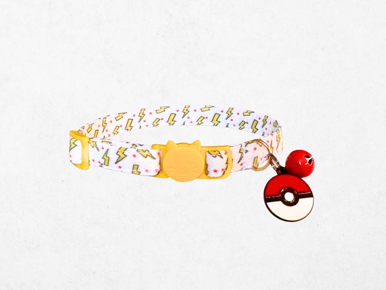 A white and yellow patterned dog collar with a yellow buckle and a red and white Pokemon-themed charm attached.