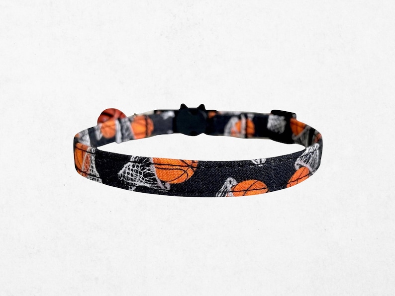 A black and orange patterned cat collar with basketballs printed on it.