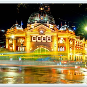 Pu&ograve; includere: Una vista notturna di un grande edificio ornato con una torre dell'orologio e una cupola. L'edificio &egrave; illuminato da luci gialle calde, e in primo piano ci sono auto e lampioni. L'edificio si riflette sul selciato bagnato.