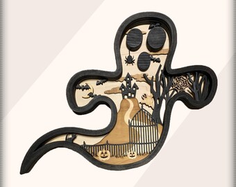 May include: A black wooden ghost cutout with a layered design. The ghost's body is hollow and reveals a scene of a spooky Halloween village with a haunted house, trees, bats, a spider web, and pumpkins.