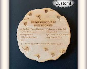 May include: Wooden cookie cutter shaped like a chocolate chip cookie with the recipe for "Great Chocolate Chip Cookies" engraved on it. The recipe includes ingredients like butter, brown sugar, milk, vanilla, baking soda, salt, flour, and chocolate chips. It also includes instructions to bake at 375 degrees Fahrenheit for 8 to 10 minutes.