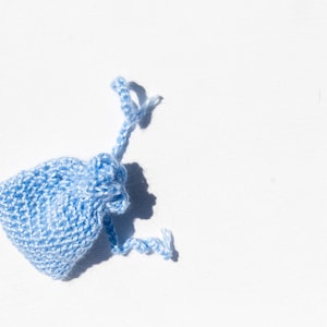 May include: A small, light blue crocheted drawstring bag against a white background.