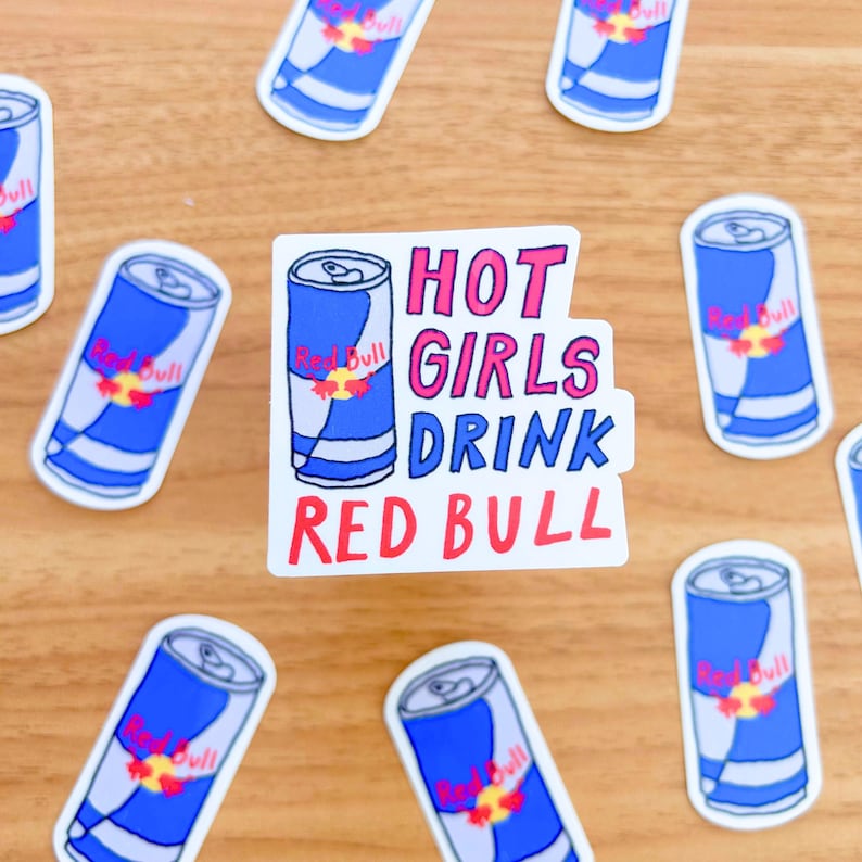 May include: A white sticker with the text "HOT GIRLS DRINK RED BULL" in pink, red, and black lettering. The sticker features a cartoon drawing of a blue and white Red Bull can.