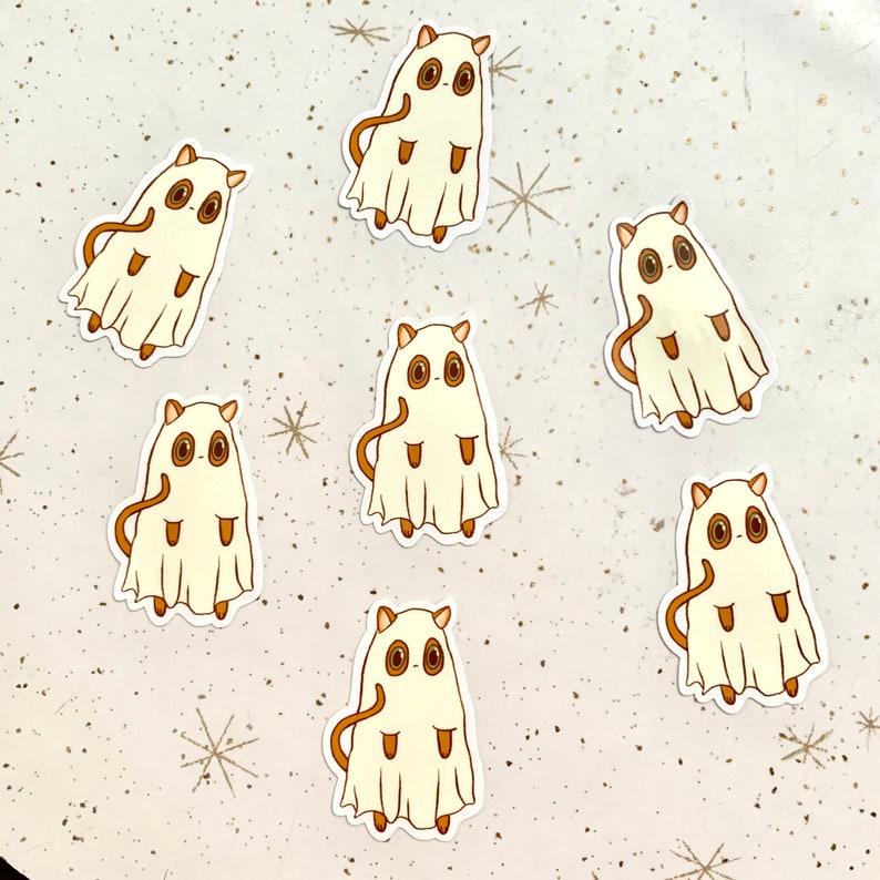 May include: Seven stickers featuring a cartoon ghost-like creature with brown eyes, ears, and tail. The creature is covered in a white sheet with a tan outline. The stickers are arranged on a speckled, off-white surface with star-shaped accents.