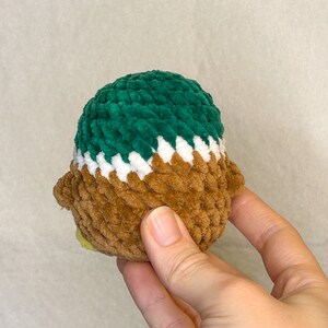 May include: A brown, white, and green crocheted plush toy in the shape of a bird.