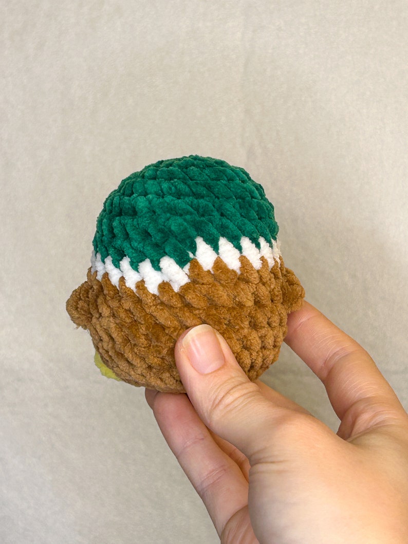 May include: A brown, white, and green crocheted plush toy in the shape of a bird.