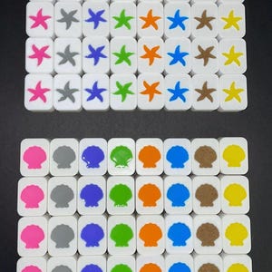 May include: A collection of white square tiles featuring colorful starfish and seashell designs. The starfish are in shades of pink, gray, blue, green, orange, brown, and yellow. The seashells are pink, gray, blue, green, orange, brown, and yellow.