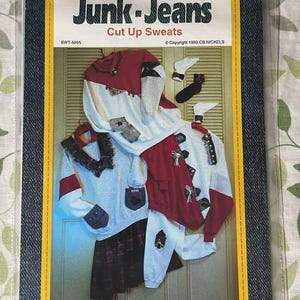 May include: A sewing pattern titled "Junk-Jeans Cut Up Sweats" featuring a collage of repurposed clothing items. The cover includes the text "Ideas for Purchased Sweatshirts" and "South Dakota Made". The design includes red, white, and gray sweatshirts and a plaid skirt.