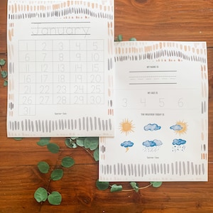 May include: A printable January calendar with a simple design featuring a light brown and gray color scheme. The calendar is decorated with small, abstract shapes. The calendar also includes a section for writing your name, age, and the weather for the day.