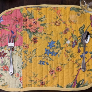 Add a touch of vibrancy to your dining table with this handmade in the USA reversible placemat set. The set features a cheerful patchwork design with floral patterns in red, yellow, blue, and pink, ideal for festive occasions and everyday use.