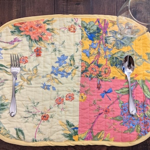 Handmade in the USA, this reversible placemat set features a lively patchwork design with floral patterns in an array of bold colors including red, yellow, blue, and pink. Perfect for adding a pop of color to your dining table.
