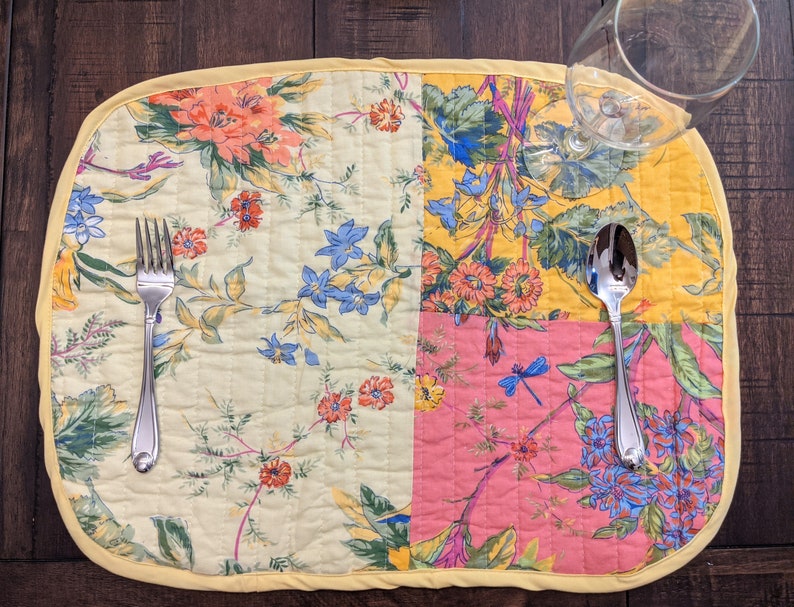 Handmade in the USA, this reversible placemat set features a lively patchwork design with floral patterns in an array of bold colors including red, yellow, blue, and pink. Perfect for adding a pop of color to your dining table.